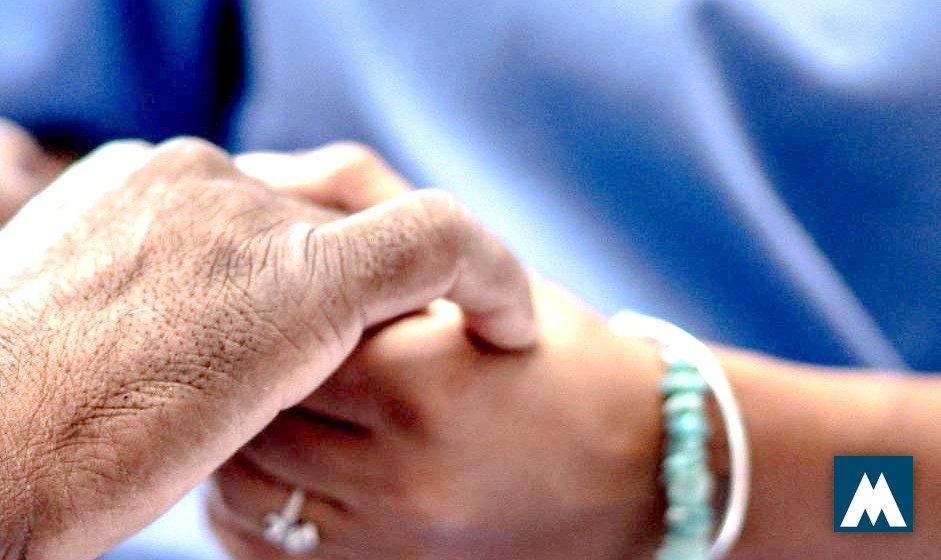 Une soignante tient la main d'une personne bénéficiaire